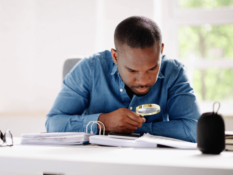 Man looking at documents with magnifying glass