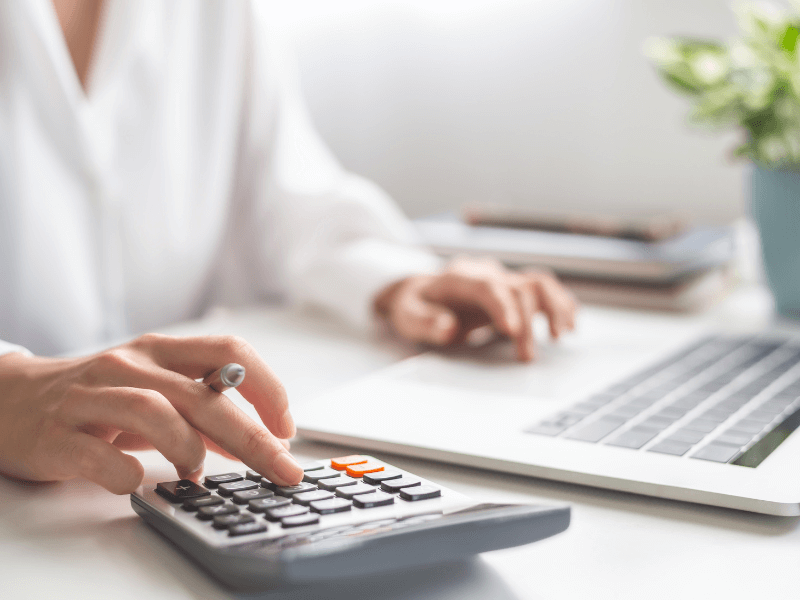 Person typing on calculator while working a laptop